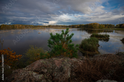 Outlook over a small lake from a hill showing the clear water and cloudy sky above it © Alexander