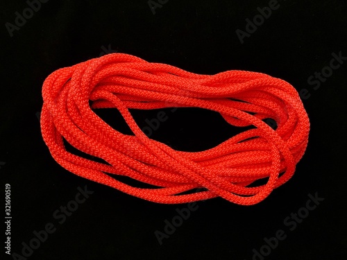 Bright nylon rope, on a black background. A long rope in a bundle.