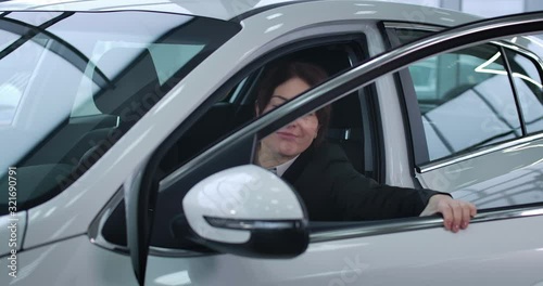 Wallpaper Mural Caucasian businesswoman in elegant suit opening car door and sitting on driver's seat. Confident adult woman buying new white automobile in dealership. Cinema 4k ProRes HQ. Torontodigital.ca