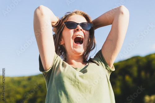 Young female with sunglasses screaming outside © madrolly