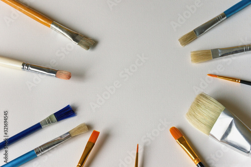 Different types of paint brushes on sheet of white paper for painting. Free space for text