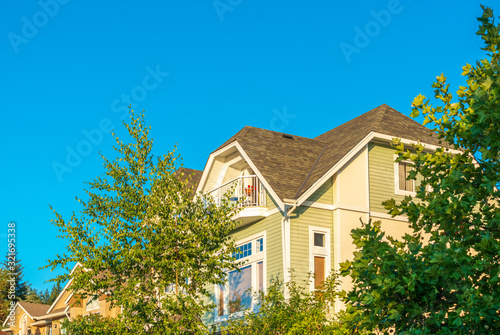 A perfect neighborhood. Houses in suburb at Summer in the north America. Top of a luxury house with nice window over blue and white sky. © karamysh
