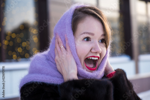 Surprised Young Woman in Purple Knitted Scarf Looking Away with Open Mouth. Winter Portrait of Excited Emotional Girl.