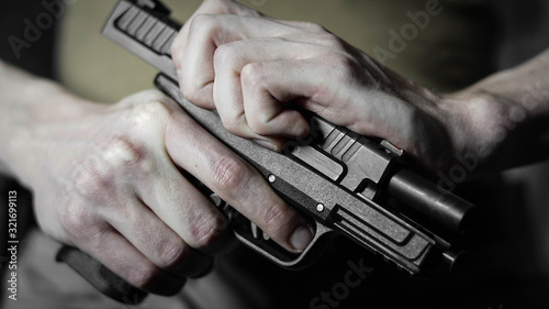 Man chambering a round in a .45 pistol. Close up with shallow depth of field.