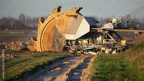 Timelapse of a giant Bucket Wheel Excavator at work in a lignite pit mine with a dirt road leading to it in the foreground