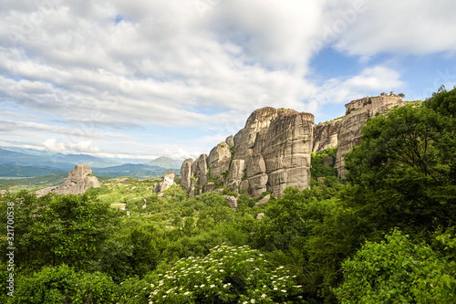 Amazing Meteora Monastery in Greece. Fantastic view at mountains and green forest against epic blue sky with clouds. UNESCO