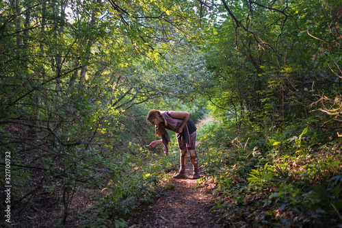 Woman examining the plants in the forest at sunset