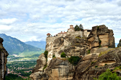 Amazing Meteora Monastery in Greece. Fantastic view at mountains and green forest against epic blue sky with clouds. UNESCO