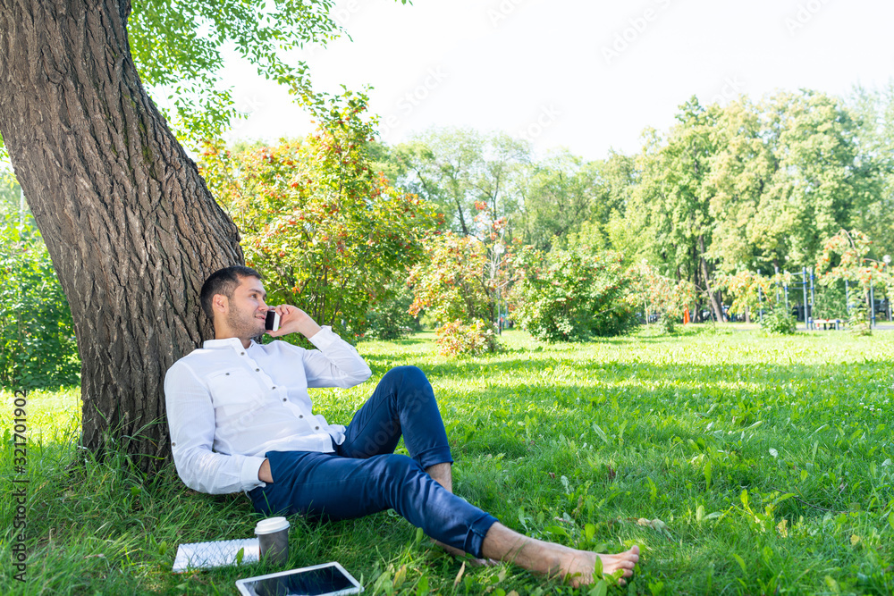 Young man talking on smartphone under tree Young man talking on smartphone under tree