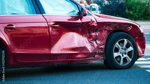 Fotografie Red car damaged and broken by accident on the road.