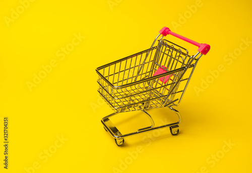 of side view empty supermarket shopping cart isolated on yellow background back
