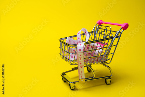 of side view empty supermarket shopping cart with a measurements in the middle isolated on yellow background back