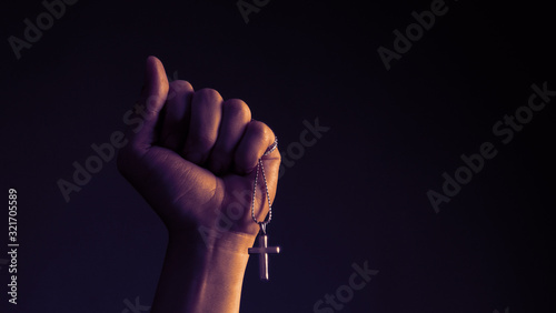 Cuadro en lienzo Close-up images of crucifix pendant necklace in man hand on black color backgrou