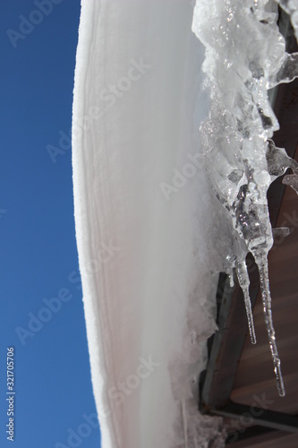 icicles on roof un der blue sky
