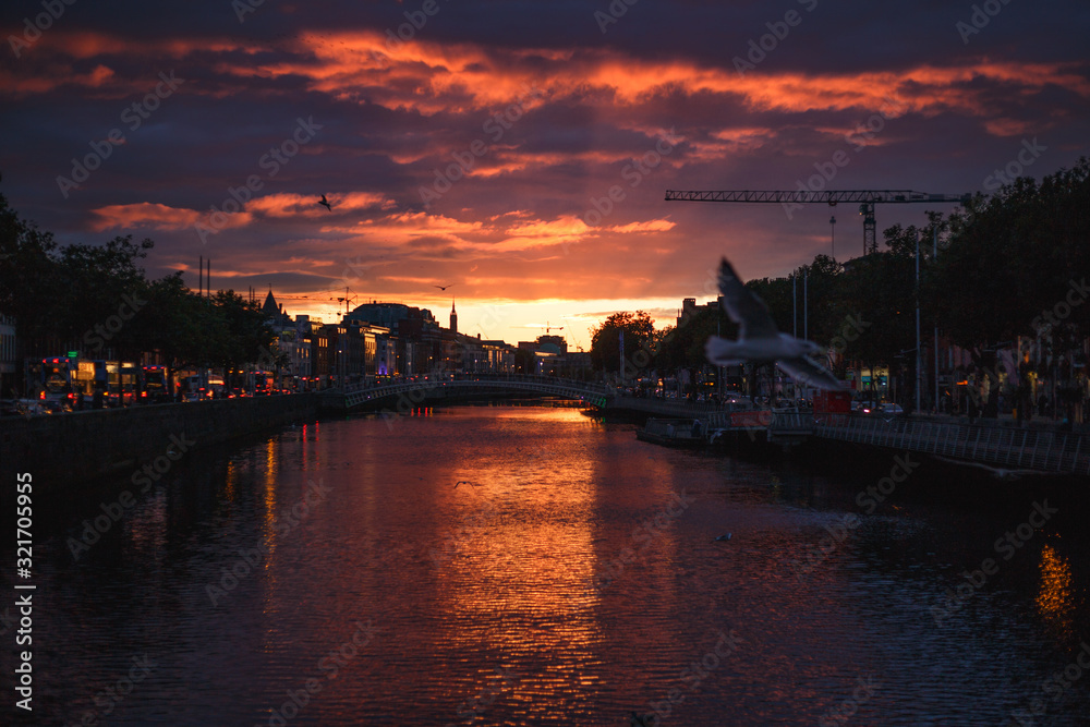 Dublin's cityscape during a colorful sunset with clouds and seagulls