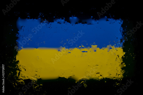 Flag of Ukraine under a glass with drops of water. Abstract photo on a black background