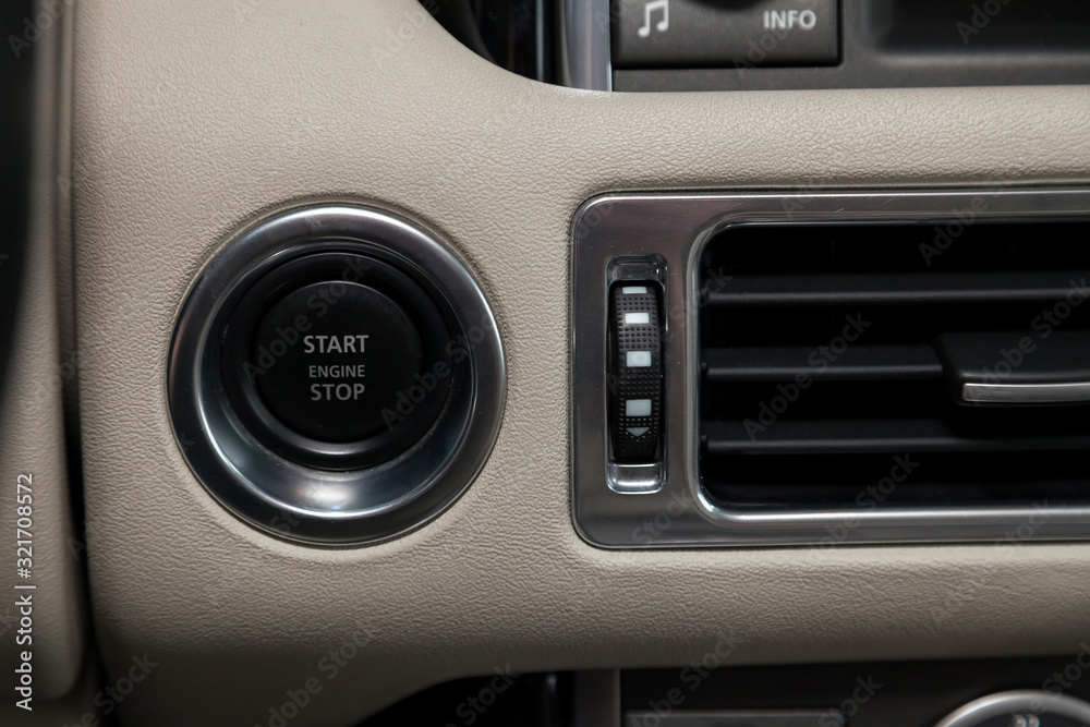 Button start and turn off the ignition of the car engine close-up on the dashboard, electric key, of modern design with elements chrome on the  beige interior panel. Auto service industry.