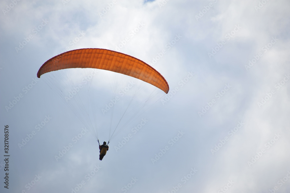Paraglider flying on colored parachute in blue clear sky at a bright sunny summer day. Active lifestyle, extreme hobbies Paraglider flying on colored parachute in blue clear sky at a bright sunny summer day. Active lifestyle, extreme hobbies