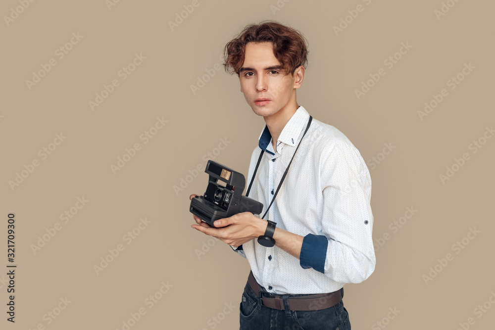 Freestyle. Stylish photographer standing isolated on gray with camera pensive Freestyle. Stylish photographer standing isolated on gray with camera pensive