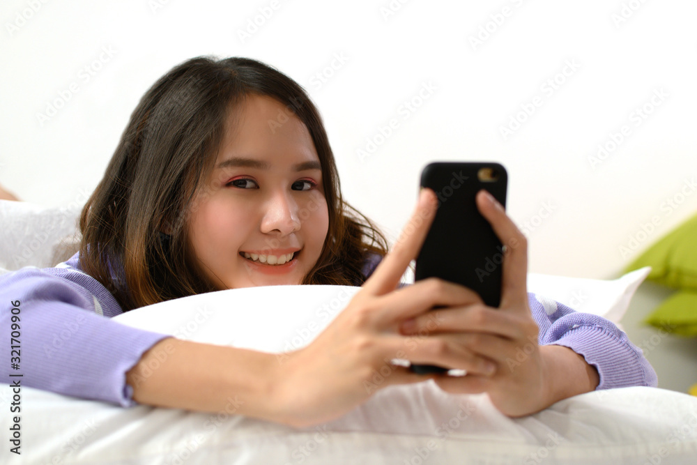 portrait happy young asian pretty woman in casual clothing smiling chat on mobile phone and lying with pillow on bed in bedroom at home, lifestyle, internet technology and social network concept portrait happy young asian pretty woman in casual clothing smiling chat on mobile phone and lying with pillow on bed in bedroom at home, lifestyle, internet technology and social network concept