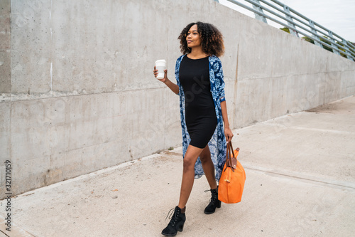 Afro american woman walking with coffee.