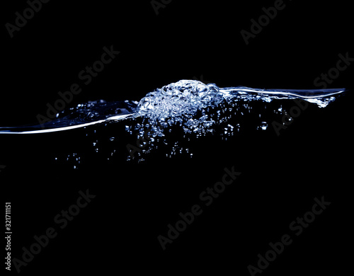 A wave of pure water with bubbles of water and air on a black background.