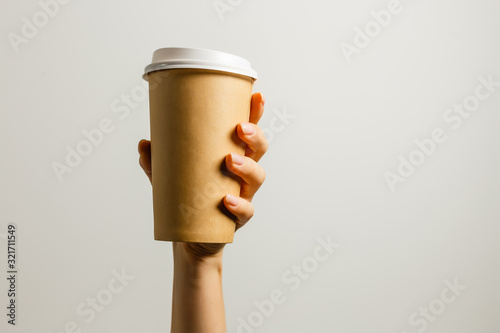 Woman holding in hand paper cup with coffee or tea. Drink coffee time. Disposable paper cup. Beautiful blond hair young girl. Casual style, white shirt and jeans. Take away. Hot beverage. Blank space © Angelov