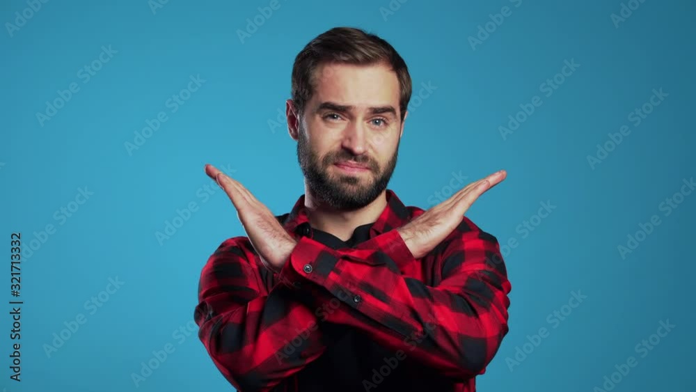 Young man with beard making no crossing hands sign, negation gesture over blue studio background Young man with beard making no crossing hands sign, negation gesture over blue studio background