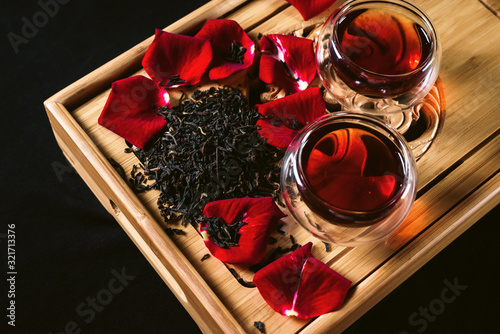 Chinese tea ceremony. Still life with traditional Asian Yunnan black tea, red tea in classic cups and rose petals as symbol of flower flavor of drink