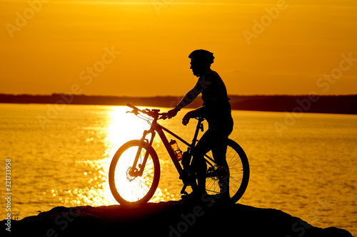 silhouette of a cyclist with sunset background. Orange sky, hobby, healthy habbits.