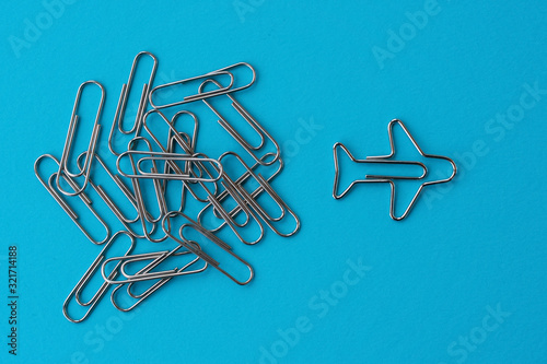 Group of ordinary paper clips with airplane shaped one on blue background. Concept of effective planning of achieving goals