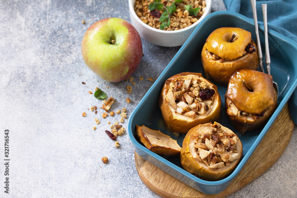 Diet menu. Healthy dessert. Baked apples with walnuts, honey and granola on slate, stone or concrete background. Copy space. Diet menu. Healthy dessert. Baked apples with walnuts, honey and granola on slate, stone or concrete background. Copy space.