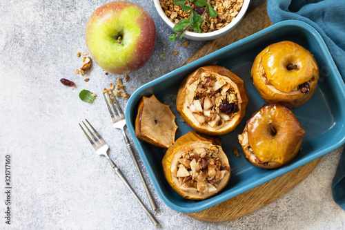 Diet menu. Healthy dessert. Baked apples with walnuts, honey and granola on slate, stone or concrete background. Top view flat lay background. Copy space.