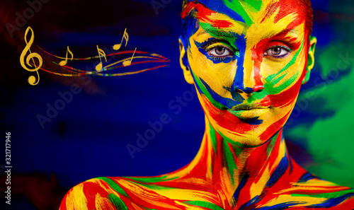 Color art face of woman for inspiration with music notes. Closeup portrait of the bright beautiful girl with colorful make-up and bodyart.