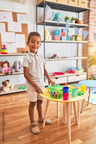 Beautiful african american toddler playing with plastic food and cutlery toy at kindergarten