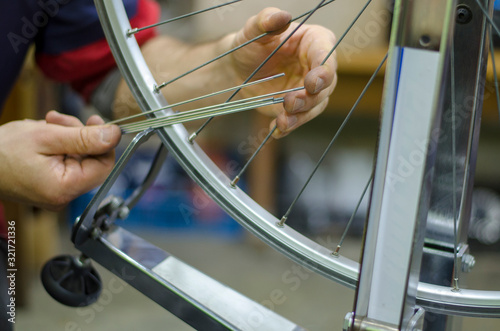 Bicycle repair, replacement of the spokes in the wheel. Bike mechanic holds the spokes in his hand photo