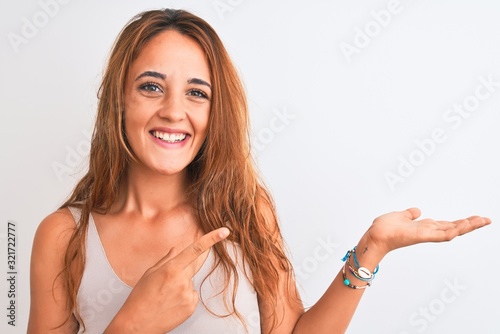 Young redhead woman stading over white isolated background very happy pointing with hand and finger
