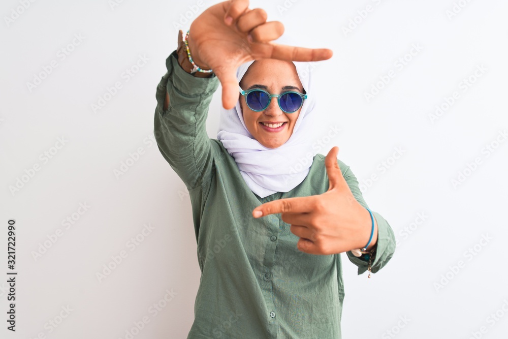 Young Arab woman wearing hijab and summer sunglasses over isolated background smiling making frame with hands and fingers with happy face. Creativity and photography concept. Young Arab woman wearing hijab and summer sunglasses over isolated background smiling making frame with hands and fingers with happy face. Creativity and photography concept.