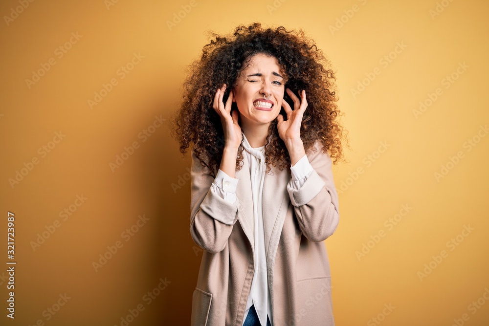 Young beautiful brunette woman with curly hair and piercing wearing casual t-shirt and diadem covering ears with fingers with annoyed expression for the noise of loud music. Deaf concept. Young beautiful brunette woman with curly hair and piercing wearing casual t-shirt and diadem covering ears with fingers with annoyed expression for the noise of loud music. Deaf concept.
