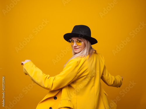 Stylish trending young woman in bright clothes on yellow background, copy space. Cool blonde