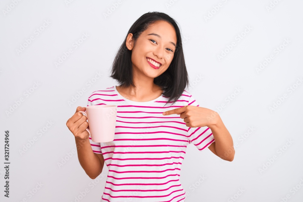 Young beautiful chinese woman drinking cup of coffee over isolated white background with surprise face pointing finger to himself