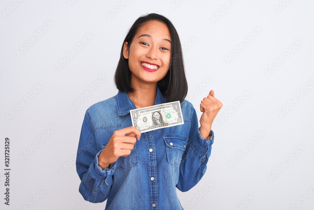 Young beautiful chinese woman holding one dollar standing over isolated white background screaming proud and celebrating victory and success very excited, cheering emotion Young beautiful chinese woman holding one dollar standing over isolated white background screaming proud and celebrating victory and success very excited, cheering emotion