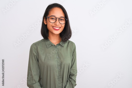 Fotografie Young chinese woman wearing green shirt and glasses over isolated white background with a happy and cool smile on face
