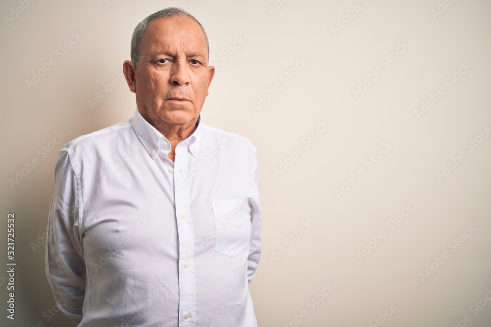 Senior handsome businessman wearing elegant shirt standing over isolated pink background with serious expression on face. Simple and natural looking at the camera. Senior handsome businessman wearing elegant shirt standing over isolated pink background with serious expression on face. Simple and natural looking at the camera.