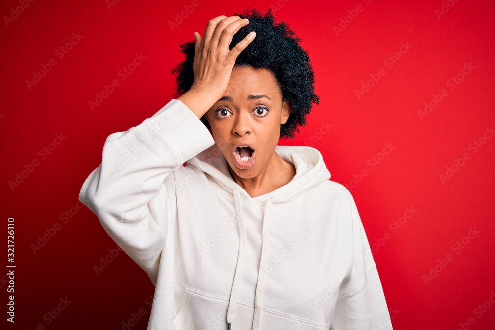 Young beautiful African American afro sportswoman with curly hair wearing sportswear surprised with hand on head for mistake, remember error. Forgot, bad memory concept. Young beautiful African American afro sportswoman with curly hair wearing sportswear surprised with hand on head for mistake, remember error. Forgot, bad memory concept.