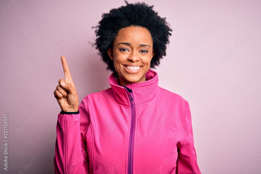 Young African American afro sportswoman with curly hair wearing sportswear doin sport showing and pointing up with finger number one while smiling confident and happy. Young African American afro sportswoman with curly hair wearing sportswear doin sport showing and pointing up with finger number one while smiling confident and happy.