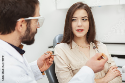 Lovely young woman talking to her dentist during medical appointment at the clinic. Perfect smile  healthy teeth concept