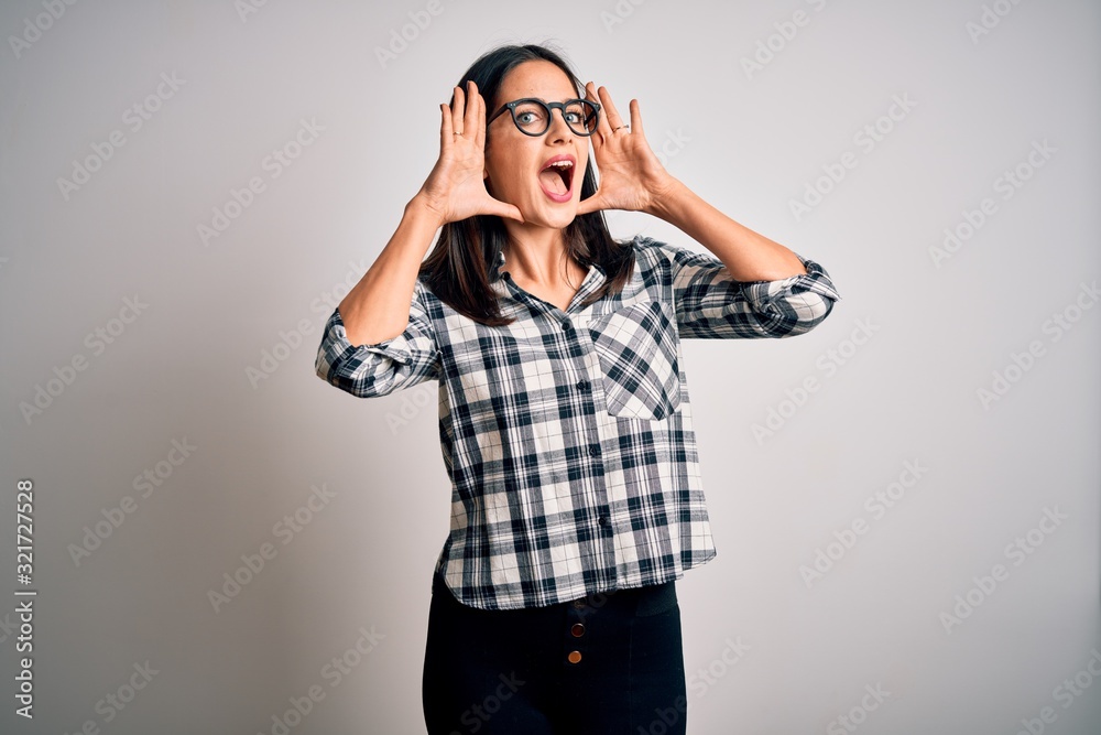 Young brunette woman with blue eyes wearing casual shirt and glasses over white background Smiling cheerful playing peek a boo with hands showing face. Surprised and exited Young brunette woman with blue eyes wearing casual shirt and glasses over white background Smiling cheerful playing peek a boo with hands showing face. Surprised and exited