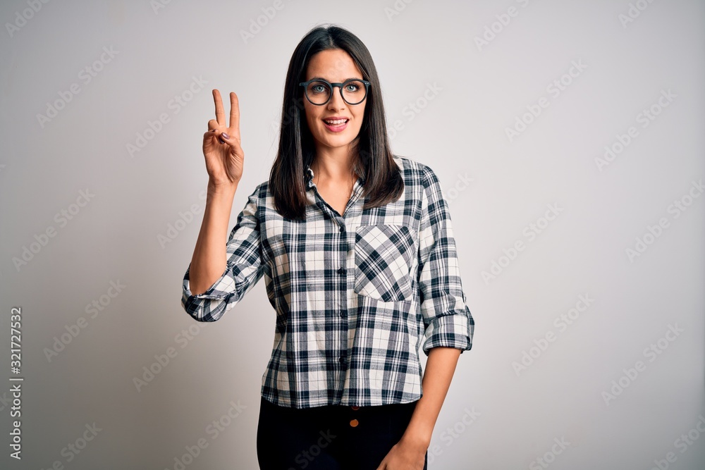 Young brunette woman with blue eyes wearing casual shirt and glasses over white background smiling looking to the camera showing fingers doing victory sign. Number two. Young brunette woman with blue eyes wearing casual shirt and glasses over white background smiling looking to the camera showing fingers doing victory sign. Number two.