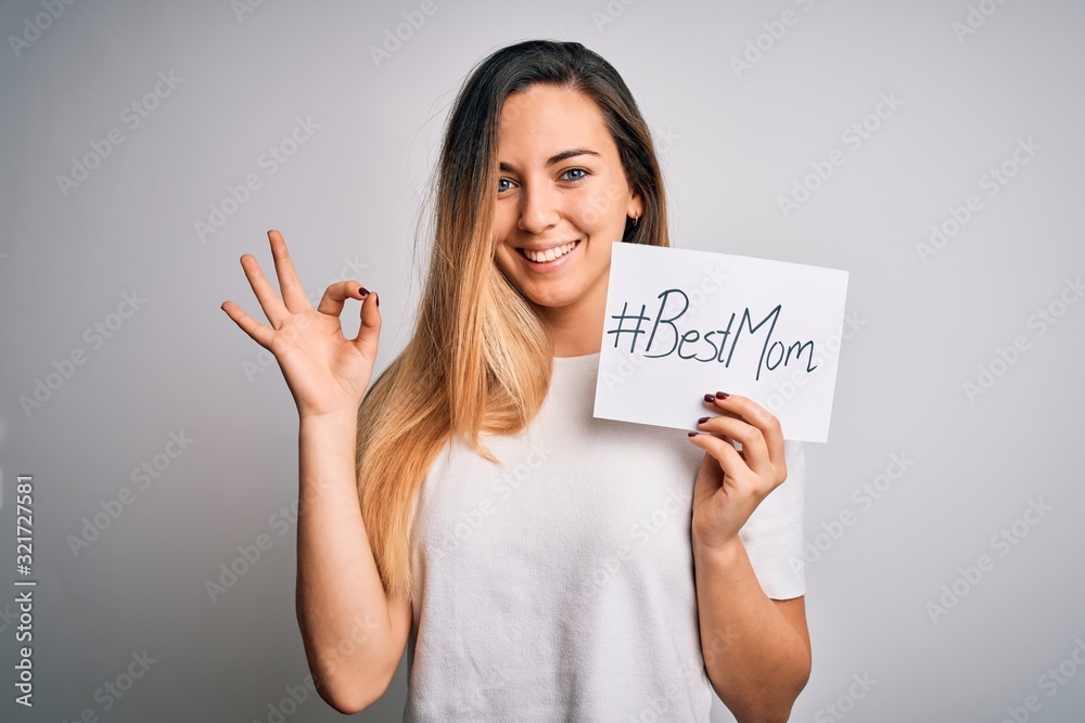 Young beautiful woman holding paper with best mom message celebrating mothers day doing ok sign with fingers, excellent symbol Young beautiful woman holding paper with best mom message celebrating mothers day doing ok sign with fingers, excellent symbol